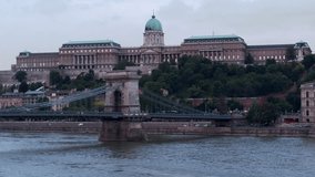 Dense traffic on and cruise ships below the Chainbridge crossing the Danube river in central Budapest - aerial video taken by a drone