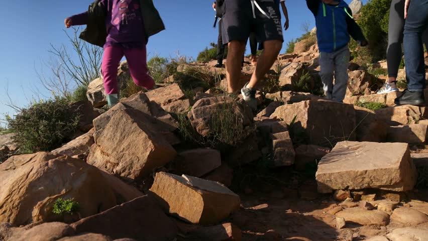 Legs & feet of hikers descending rocky Lions Head hiking path pan to blue ocean skyline view with Robben Island