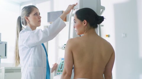 In the Hospital, Mammography Technologist / Doctor adjusts Mammogram Machine for a Female Patient. Modern Technologically Advanced Clinic with Professional Doctors.  Shot on RED EPIC-W 8K Camera.