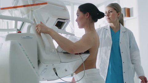 In the Hospital, Mammography Technologist / Doctor Pushes Button on Mammogram Machine Activating Female Patient Scan. Friendly Doctor Explains Importance of Breast Cancer Prevention Screening. 4K UHD.