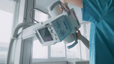 In the Hospital, Female Technician adjusts X-Ray Scanner / Machine. Modern Hospital with Technologically Advanced Medical Equipment and Professional Personnel. Shot on RED EPIC-W 8K Camera.