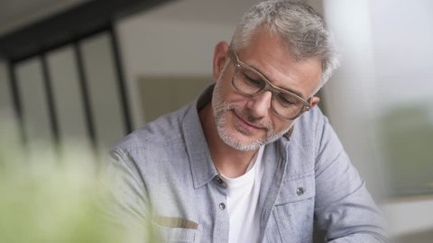 Middle-aged guy with trendy eyeglasses relaxing at home
