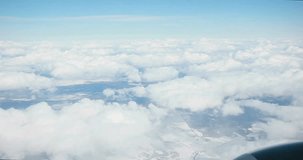 Stunning footage of aerial view above clouds from airplane window with blue sky. view from the airplane window to the blue sky and white clouds. view of the earth from the sky through the clouds