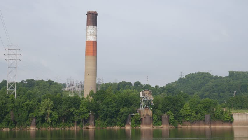An implosion of a factory's old smoke stack on the banks of the Ohio River. Pittsburgh suburbs. Shot at 60fps for optional slow motion use. Audio included.  	 Royalty-Free Stock Footage #1012078058