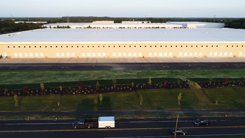 Large Warehouse on rural road fly by at sunset