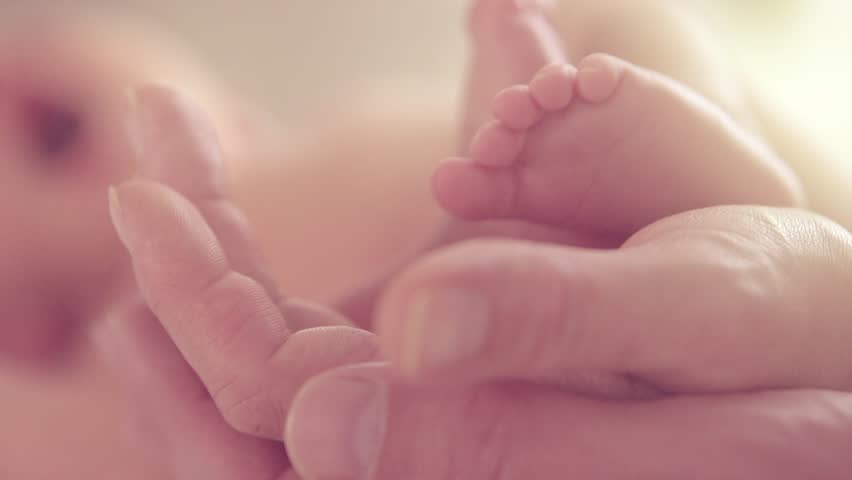 Baby feet in mother and father hands. Tiny Newborn Baby's feet on hands closeup. Mom, dad and Child. Healthy and Happy Family concept. Beautiful video of Parenthood, adoption 4K Slow motion 240fps