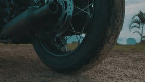 Closeup of motorcycle wheel moving over beautiful mountain view and sky background - video in slow motion