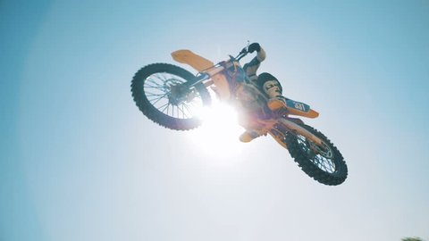 A motorcycler is flying over on his bike after jumping