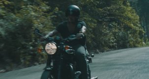 Side view of cool traveler driving his chopper motorbike on tropical island road with green trees background  view during summer day - video in slow motion