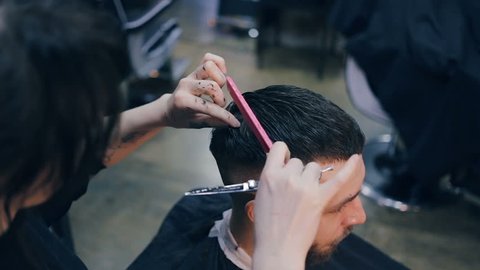 Men's hairstyling and haircutting in a barber shop or hair salon. Grooming the hair. Barbershop. Woman hairdresser doing haircut adult men in the men's hair salon. Haircutter in the workplace