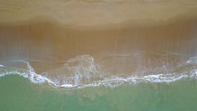Aerial view of looping turquoise ocean wave reaching the coastline. Beautiful tropical beach from top view. Andaman sea in Thailand. Summer holiday vacation concept. 4K video taken from drone.