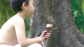 Chinese boy eating ice cream and hand holding melting waffle cone in hand on summer light nature background.