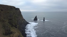 Drone view of black sand beach in south of Iceland Reynisfjara Beach. This Black Sand Beach and the rock formations are stunningly beautiful. Seabird flying along the cliffs captured  by arial shot - Powered by Shutterstock - Get 15% off with code: PIKWIZARD15