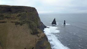 Drone view of black sand beach in south of Iceland Reynisfjara Beach. This Black Sand Beach and the rock formations are stunningly beautiful. Seabird flying along the cliffs captured  by arial shot - Powered by Shutterstock - Get 15% off with code: PIKWIZARD15
