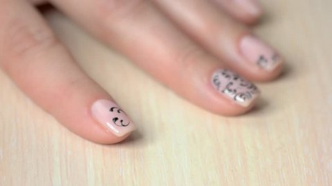 The process of nail design in beauty salon. Manicurist painting black lace on female nails. Talent and skills of manicure master.