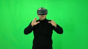 Adult man works with virtual reality helmet and has a fun green-screen