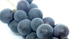 A bunch of black grapes rotating over white background
