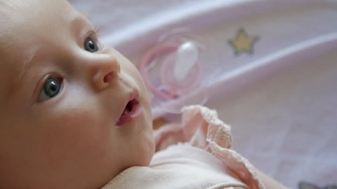 Close up of a happy three month old baby girl wriggling around and laying on a soft blanket. Video de stock