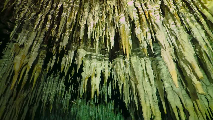 Underwater cenote with stalactites. Cave limestone formation under the water surface with light reflection. Cenote tunnel exploration.
