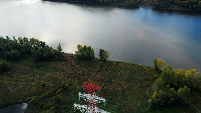 electrical transmission tower on river bank among plants