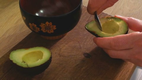 hand that takes the pulp with a spoon from a avocado
