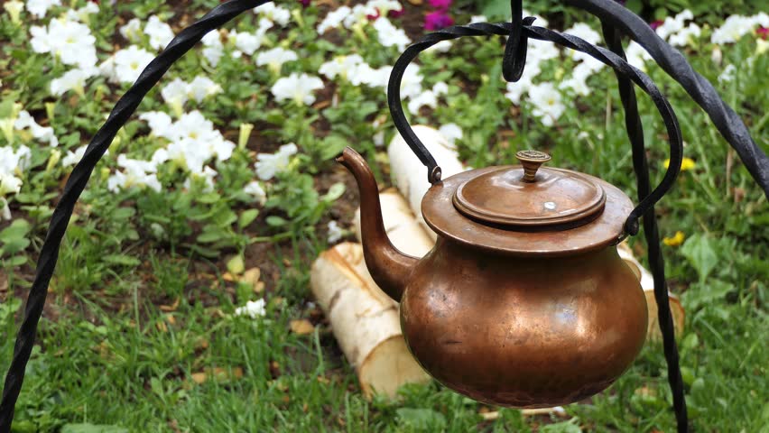Copper metal kettle hanging on an iron wire for warming up on fire
