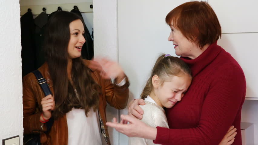 Attractive female leaving apartment, saying goodbye to senior woman with crying little girl