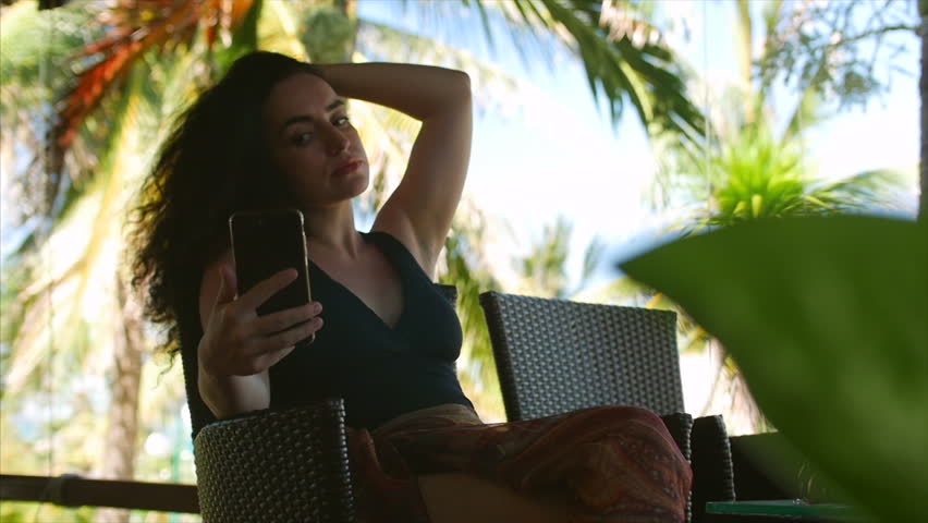 Beautiful young woman makes selfie by cell phone, attractive caucasian girl photographing herself.