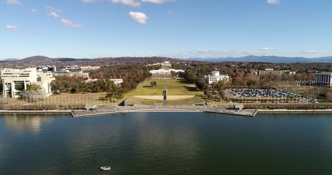 New Australian parliament on capitol hill in Canberra from lake Burley griffin waterfront to grass lawn avenue on a sunny day.
