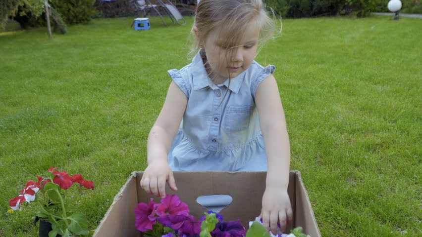 Funny little girl work with flowers in the graden