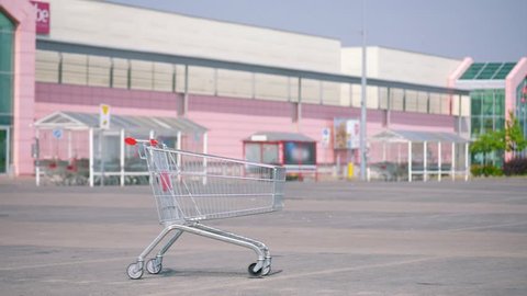 Pushing an empty shopping cart at parking. Shopping trolley in a parking lot near a supermarket. 
