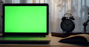 Laptop with green screen. Dark office. Dolly right to left. Perfect to put your own image or video.