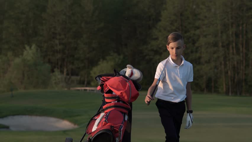 Young golfer fidgets  while waiting to take his shot on the golf course