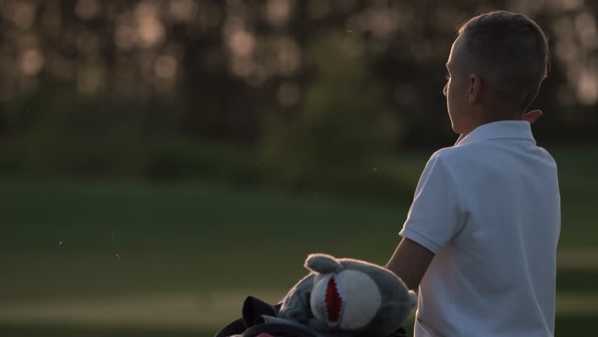 Young golfer fidgets  while waiting to take his shot on the golf course