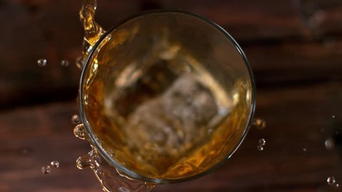 Ice dropped into glass of whisky in super slow motion. Shot with high speed cinema camera, 1000fps.
