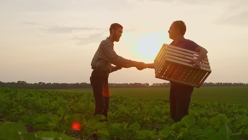 Two businessman farmers shake hands with each other firmly. They talk on the field against a beautiful sunset, they use a tablet. Deal | Shutterstock HD Video #1012158401