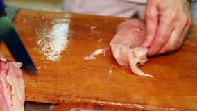 The cook cuts the chicken breast in half, raw chicken, chef cooks chicken breasts