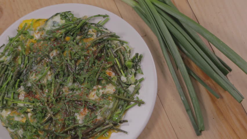 Asparagus omelette. CU of an asparagus omelette displayed on a wooden table with green onions next to it.