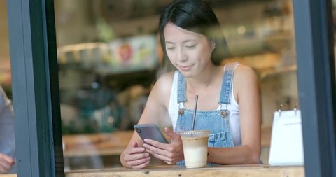 Woman use of mobile phone inside coffee shop