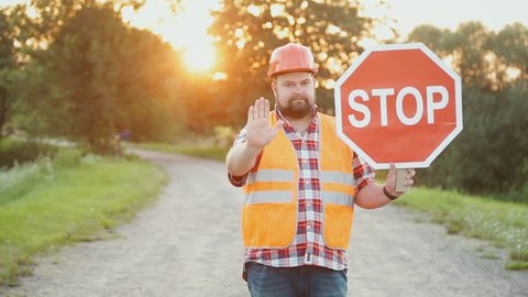 A construction road worker stopping traffic, holding a stop sign.