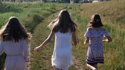 Young girls running on summer countryside meadow road - teenagers triple sisters twins