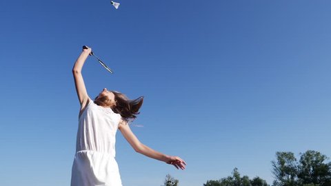 Teenager young girl on summer countryside jump hit the shuttlecock playing badminton