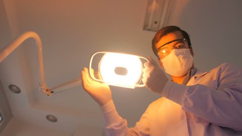 Dentist turns the Light of dental lamp on, Patient point of view. 庫存影片