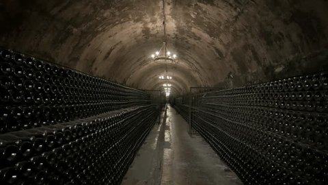 Wine Cellars of the Winery. Old Bottles with Champagne are Kept in Racks. Stone Arches Covered with Mold