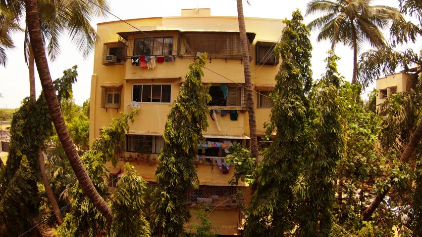 four-storied house in bedroom community clothes dry wind swaies palms and green trees Mumbai