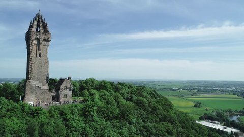4K aerial footage of the tower of the Wallace Monument on the summit of Abbey Craig near Stirling in Scotland.