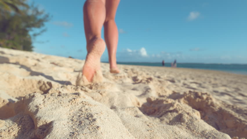 SLOW MOTION:, LOW ANGLE, CLOSE UP, DOF Unrecognizable woman running in the hot summer sun along the sunny exotic shore in Cook Islands. Carefree girl takes off her flip flops and runs in the sand. Royalty-Free Stock Footage #1012187819