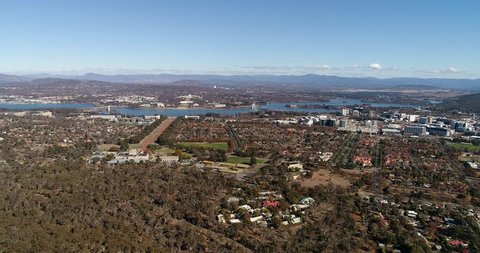 Canberra city suburbs around lake Burley Griffin on a sunny day – aerial panning in view of government district and city CBD towers.
