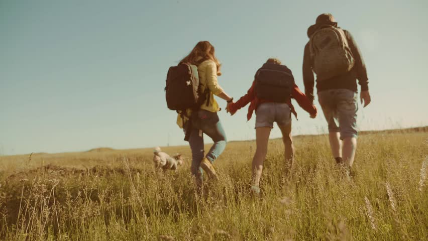 Happy family slow motion video walking on nature boy girl and mom in a field on trekking trip. tourists with backpacks traveling. happy lifestyle family travel tourism concept