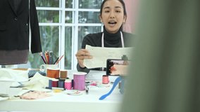 Fashion designer at work. Young chinese fashion designer and tailor doing a video blog and video review at her home office. Small business start up concept.